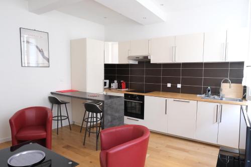 une cuisine avec des placards blancs et des chaises rouges dans l'établissement sunside cannes, à Cannes