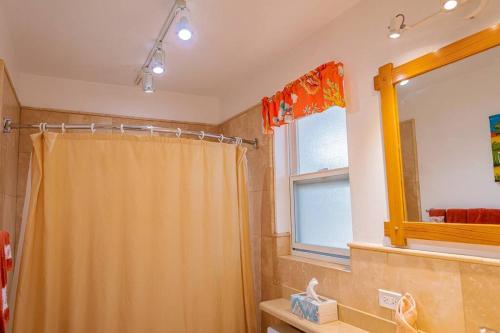 La salle de bains est pourvue d'un rideau de douche et d'une fenêtre. dans l'établissement Villa by the sea, à Five Islands Village