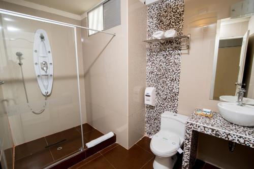 y baño con aseo, lavabo y ducha. en Suche Park Hotel, en Piura