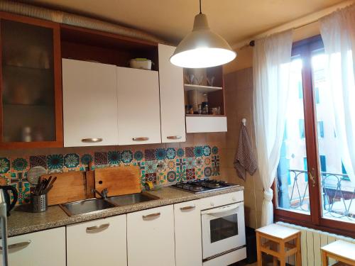 eine Küche mit weißen Schränken, einem Waschbecken und einem Fenster in der Unterkunft Two steps from Rialto bridge in Venedig
