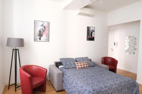 - une chambre avec un lit et deux chaises rouges dans l'établissement sunside cannes, à Cannes