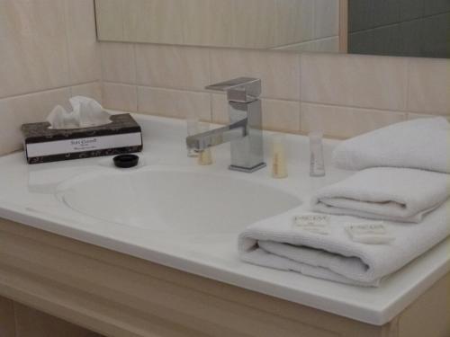 La salle de bains est pourvue d'un lavabo, de serviettes et d'un robinet. dans l'établissement Glenelg Motel, à Adélaïde