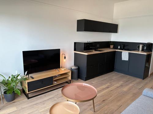 Il comprend une cuisine avec des placards noirs et une télévision à écran plat. dans l'établissement Appartement face mer Le Croisic , piscine privée et plage, au Croisic