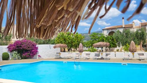 a pool with chairs and umbrellas and a house at Hotel Residence Torre Del Porto in Mattinata