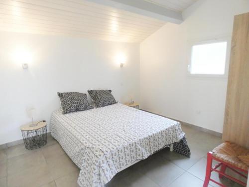 een witte slaapkamer met een bed en een raam bij Pierron in Linxe