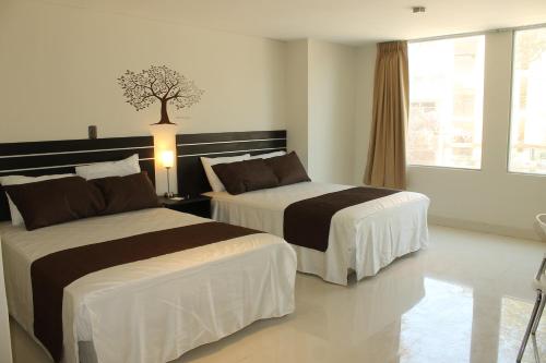 una habitación de hotel con 2 camas y un árbol en la pared en Suche Park Hotel, en Piura