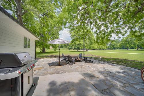 a patio with a table and chairs and an umbrella at Well-Appointed Tulsa Home with Fire Pit and Patio! in Tulsa