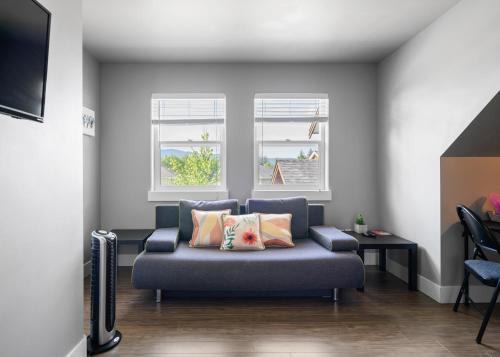 a living room with a couch and two windows at Separate Suite in Prestigious Linley Valley in Nanaimo