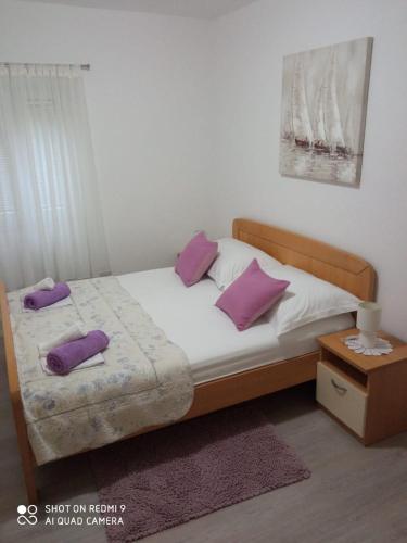 a bedroom with a bed with purple pillows on it at Apartments Šime in Trogir
