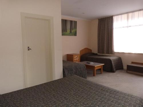 a hotel room with two beds and a window at Glenelg Motel in Adelaide