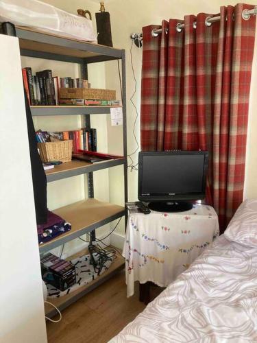 a bedroom with a tv sitting on a table with a bed at The Cabin in Hockham