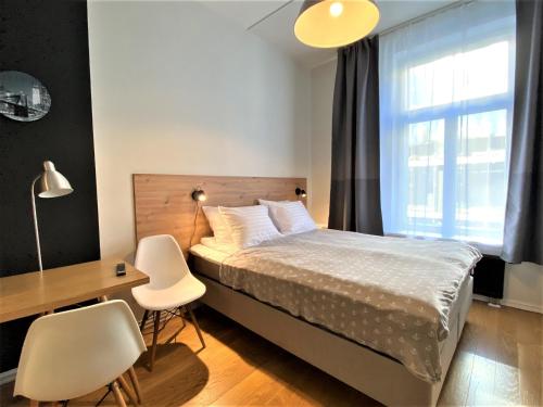 een slaapkamer met een bed, een bureau en een raam bij Rotermann Central Apartments in Tallinn