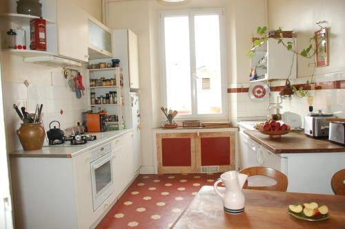 une cuisine avec des armoires blanches, une table et une fenêtre dans l'établissement Appartement centre ville avec parking gratuit, à Chambéry
