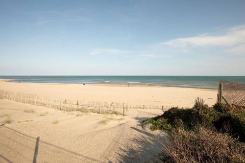 a sandy beach with a fence and the ocean at Studio 4pers climatisé accès direct plage in Marseillan