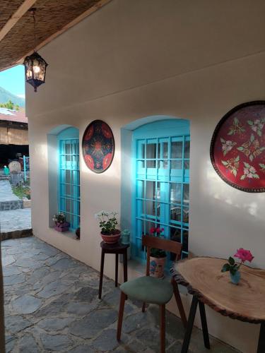 Habitación con ventanas azules, mesa y sillas. en Guest House Ruh Achari, en Sheki
