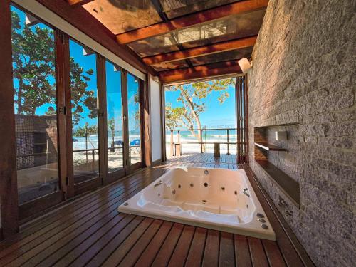 a bath tub in the middle of a room with windows at Hotel Nacional Inn Ubatuba - Praia das Toninhas in Ubatuba