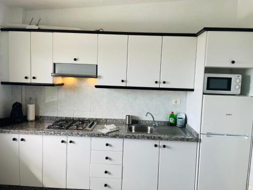 cocina con armarios blancos, fregadero y microondas en Apartamentos azayara en Frontera