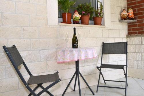 a table with a bottle of wine and two chairs at House with swimming heated pool next to the river in Podstrana
