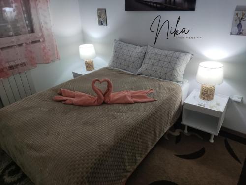 zwei rosa Flamingos auf einem Bett mit zwei Lampen in der Unterkunft Apartman Nika in Kragujevac