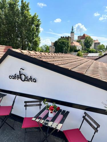a table with two chairs and a sign on a building at Penzion, vinný sklep a café Bárta in Mikulov