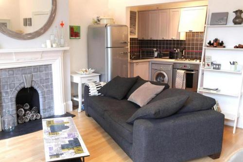 ein Wohnzimmer mit einem Sofa und einer Küche in der Unterkunft Trendy 2BD flat in West Hampstead in London