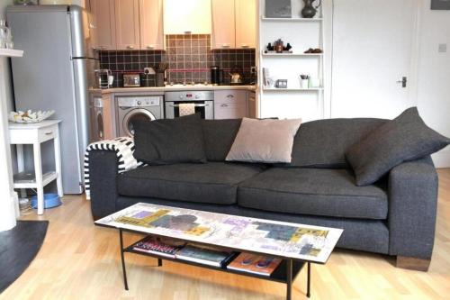 ein Wohnzimmer mit einem Sofa und einem Tisch in der Unterkunft Trendy 2BD flat in West Hampstead in London