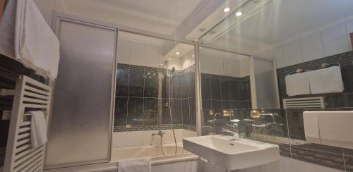 a white bathroom with a sink and a shower at La Perle Apartments in Zermatt