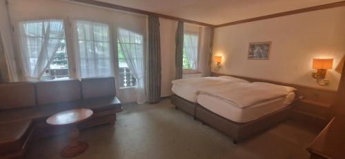 1 dormitorio con 1 cama, escritorio y ventanas en La Perle Apartments, en Zermatt