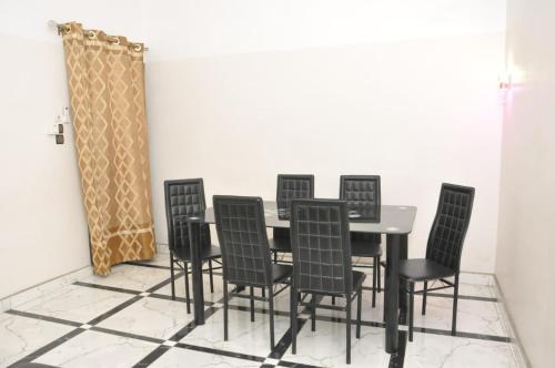 a dining room with a table and black chairs at Maison Houdji, près de la lagune in Cotonou