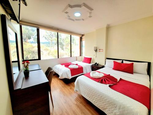 Hotel Loja Bella في لوخا: غرفة نوم بسريرين ومخدات حمراء