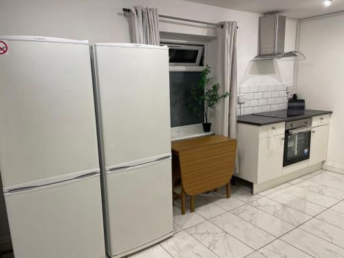 uma cozinha com um frigorífico branco e uma mesa em Double bedroom with bathroom en suite and a large balcony for short or long let in London Canary Wharf E14 em Londres