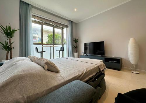 Schlafzimmer mit einem Bett, einem TV und einem Fenster in der Unterkunft Reinapart Patacona Beach 36 in Valencia