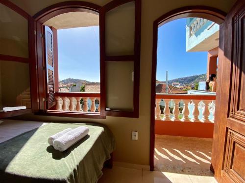 um quarto com uma cama e vista para uma varanda em Pousada Paraíso dos Corais em Arraial do Cabo