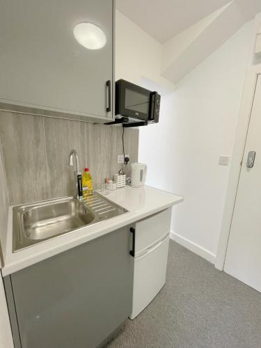a small kitchen with a sink and a microwave at Cosy Bright Studio Apartment Close to Wembley Stadium in London
