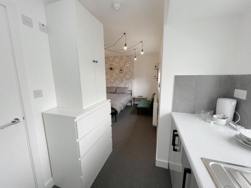 a white kitchen with a sink and a bedroom at Cosy Bright Studio Apartment Close to Wembley Stadium in London
