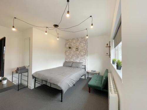 a bedroom with a bed and a green chair at Cosy Bright Studio Apartment Close to Wembley Stadium in London