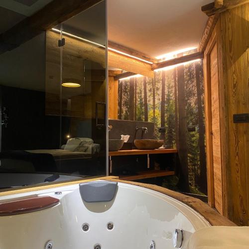 a bath tub in a bathroom with a forest view at Hotel Rio Bianco in Panchia