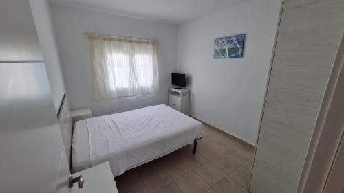 カンブリルスにあるApartamento en Cambrilsのベッドと窓が備わる小さな白い客室です。