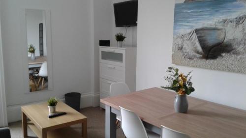 a living room with a dining room table and a television at AzZule Apartments in Tynemouth