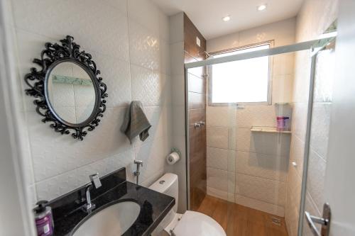 a bathroom with a sink and a mirror on the wall at Lindo apartamento 2 quartos com wifi in Rio das Ostras