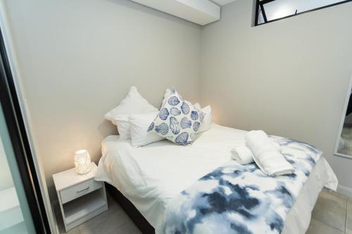 a white bed with blue and white pillows on it at 10 on Bellamare near the Beachfront in Summerstrand