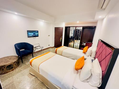 a hotel room with two beds and a chair at The Elite Residence Dhaka in Dhaka