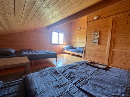 a bedroom with two beds in a wooden cabin at Vītolu nams - atpūta ar saunu un makšķerēšanu in Durbe