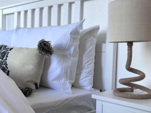 a white bed with white pillows and a lamp at Studland View Cottage in Studland