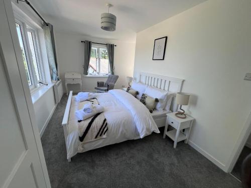 a bedroom with a white bed and a chair at Studland View Cottage in Studland