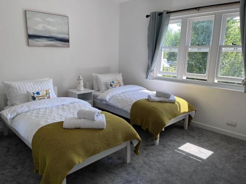 two beds in a room with two windows at Studland View Cottage in Studland