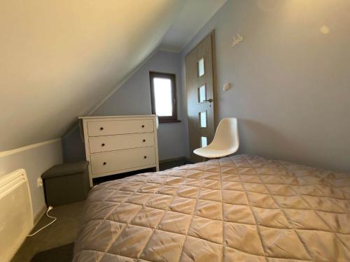 a bedroom with a bed and a dresser and a window at Leśne Zacisze domki letniskowe in Lipnica