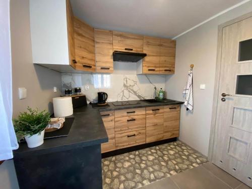 a kitchen with wooden cabinets and a black counter top at Leśne Zacisze domki letniskowe in Lipnica
