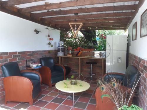 eine Terrasse mit Stühlen, einem Tisch und einem Kühlschrank in der Unterkunft Cabañas Limón y Manzana en Finca Maracuba in Jardin