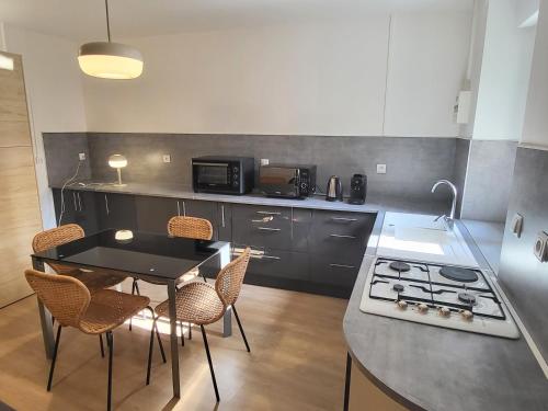 une cuisine avec une table, des chaises et une cuisinière dans l'établissement Appartement 1 Chambre, cuisine, coin salon, salle de bain, à Saint-Claude